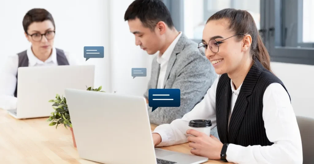 Team members in an office using laptops with chat bubble icons to manage customer conversation management tasks.